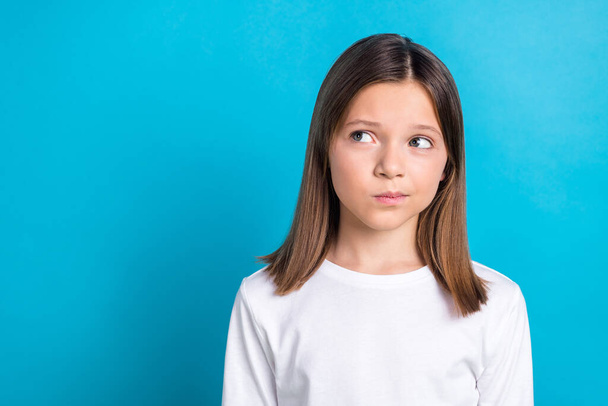 Photo portrait of charming schoolgirl look skeptical doubtful empty space dressed stylish white clothes isolated on blue color background. - Foto, Imagem