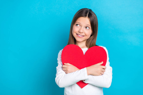 Photo of friendly schoolgirl with straight hairdo dressed white shirt hug red heart look empty space isolated on blue color background. - Photo, Image