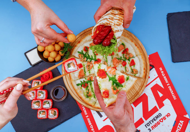 pizza shawarma sushi y bolas de patata sobre un fondo azul para un menú de restaurante en línea - Foto, Imagen