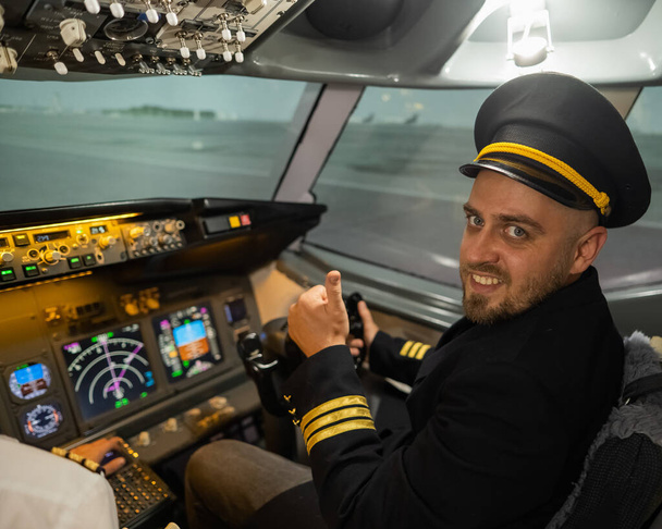 Кавказький бородатий чоловік посміхається під час симулятора польоту. Пілот у кабіні з пальцями вгору. - Фото, зображення