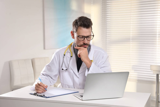 Pediatrician consulting patient online at table in clinic - Photo, image