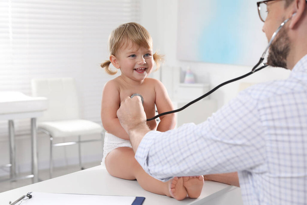 Pediatrician examining baby with stethoscope in clinic - Valokuva, kuva