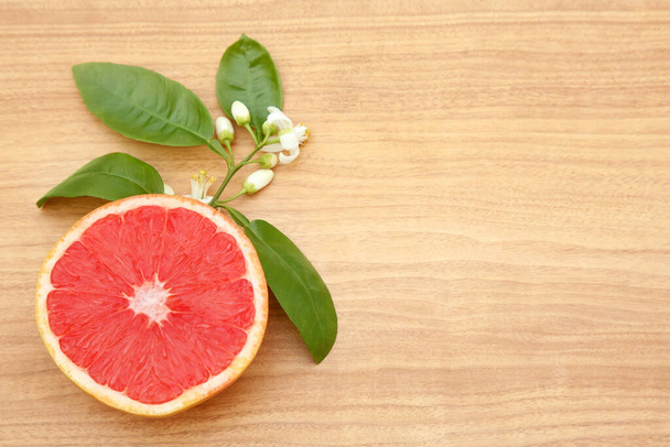 Cut fresh ripe grapefruit and green leaves on wooden table, flat lay. Space for text - Foto, Bild