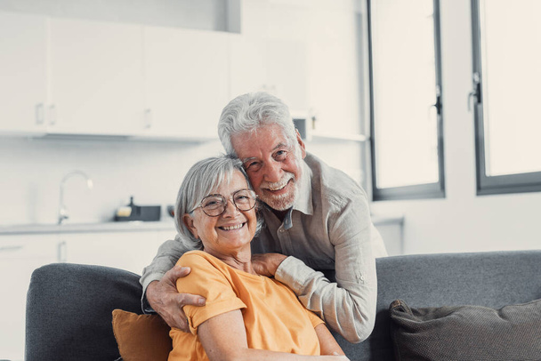 Headshot muotokuva hymyilevä vanhusten 60-luvun aviomies ja vaimo istua rentoutua sohvalla halaus halaus, onnellinen kypsä vanha pari levätä sohvalla olohuoneessa syleilyssä katso kameran näyttää rakkautta ja hoitoa
 - Valokuva, kuva