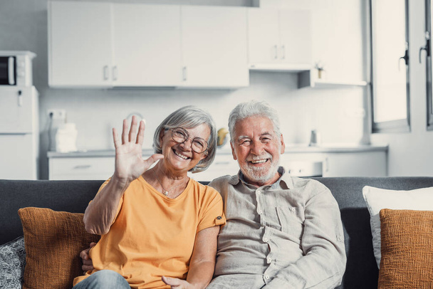 Sixty years couple, elderly parents communicates with grown up children using modern technologies makes video call, wave hands gesture of hello or goodbye sign, older generation and internet concept - Photo, Image