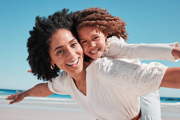 Portrait, mother and girl at a beach for airplane, game and bonding, happy and excited for travel, playing or family summer on blue sky. Face, piggyback and mom with child at a sea in Mexico. - Foto, Imagem