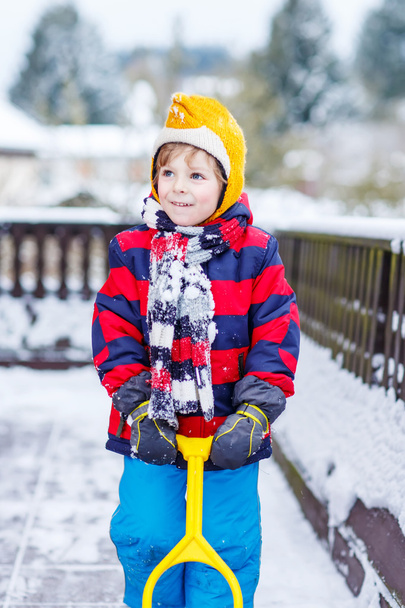 Αστεία μικρό αγόρι με πολύχρωμα ρούχα χαρούμενος για χιόνι, σε εξωτερικούς χώρους - Φωτογραφία, εικόνα