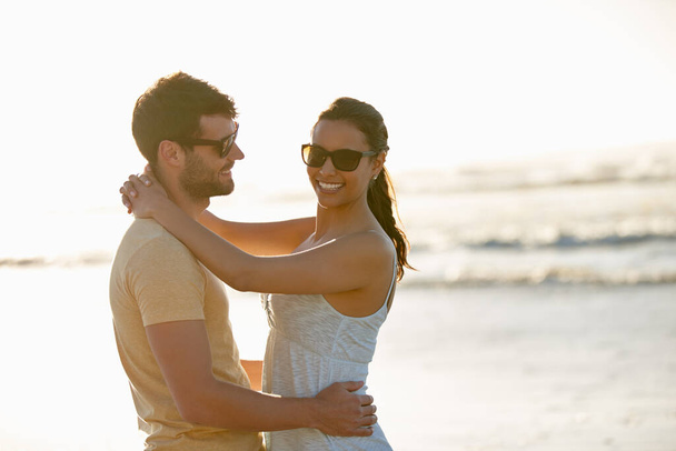 Wir haben dieses Sommergefühl. ein romantisches junges Paar lächelt mit dem Meer im Hintergrund - Foto, Bild
