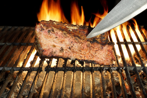 Chef kés a grillezett húst vágjuk. Láng háttérben. - Fotó, kép