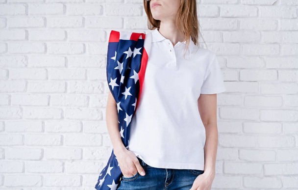 アメリカの国旗を背景にした女性用の白いポロシャツ、モックアップデザイン。室内撮影 - 写真・画像