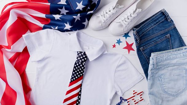 Dzień Pamięci USA, Dzień Prezydenta, Dzień Weterana, Dzień Pracy lub obchody 4 lipca. Projekt makiety biała koszulka polo do logo, widok z góry na białe drewniane tło z flagą USA, buty i dżinsy - Zdjęcie, obraz