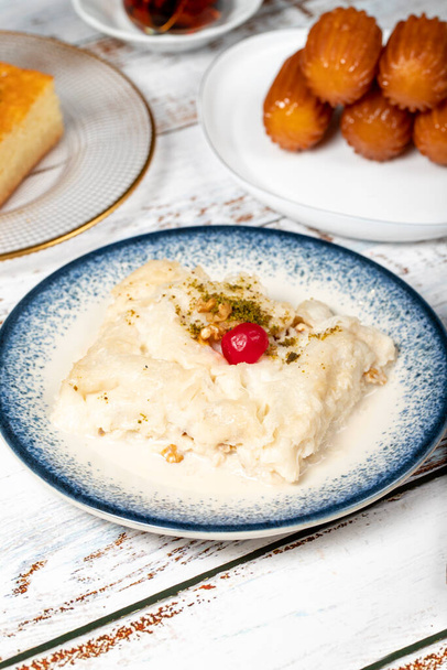 Gullac, revani, tulumba and bread kadayif dessert with cream on a wood floor. Ramadan sweets. Traditional Turkish cuisine delicacies - Photo, Image