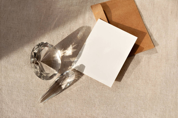 Elegáns esztétikai üzleti márka sablon, üres papír kártya mock up másolás tér és üveg kristályok reflexiók és napfény árnyékok semleges bézs asztal háttér - Fotó, kép