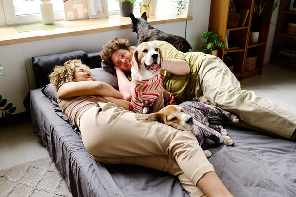 Jeune couple multiethnique se relaxant au lit avec leurs petits membres de la famille - Photo, image