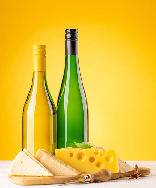 Erilaisia juustoja aluksella ja valkoviiniä. Keltaisen taustan ja kopiotilan yli - Valokuva, kuva
