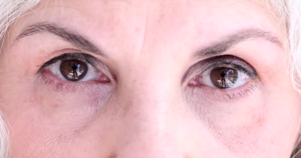 Ojos marrones de mujer mayor hace ejercicio relajante para los ojos. Hiperopía miopía astigmatismo y glaucoma en la jubilación - Imágenes, Vídeo