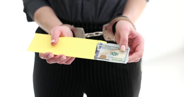 Une femme menottée tient une enveloppe avec de l'argent. Un politicien ou un PDG arrêté pour corruption - Séquence, vidéo