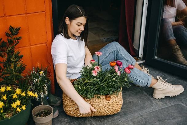 Florist working at a flower shop. Woman taking care of us flowers, arranging them into a big basket. - Fotoğraf, Görsel