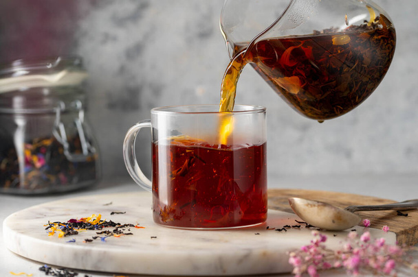 Pouring freshly brewed black loose leaf tea in glass cup. Lifestyle drinking tea - Foto, Imagen