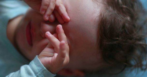 Tired baby rubbing eye and face with hands, sleepy child infant - Foto, Bild