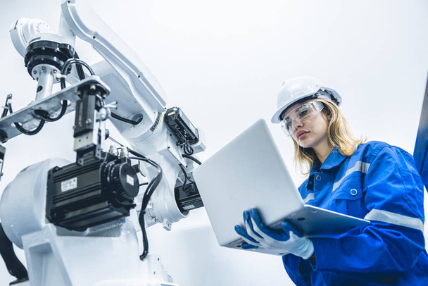 Ingeniera trabajadora que trabaja con brazo robótico en fábricas de investigación de laboratorio de producciones - Foto, Imagen