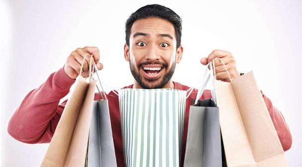 Wow, sale and portrait of man with shopping bag in studio, excited for discount or purchase on white background. Deal, face and indian guy with product from shop, mall or market while posing isolated. - Foto, Bild