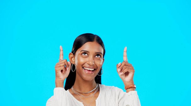 Mockup, face and Indian woman pointing up, promotion and success on a blue studio background. Portrait, female and lady with gesture for motivation, inspiration and carefree with decision and choice. - Фото, зображення
