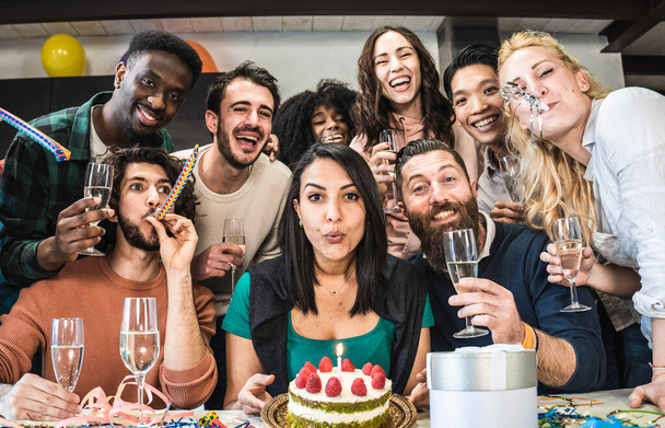Multi-ethnische Freunde haben Spaß bei Geburtstagsfeier - Junge Leute suchen Kamera bei Geburtstagsfeier für Gruppenfoto - Marokkanerin bläst Kerze auf Kuchen aus, bevor sie ihr Geschenk auspackt - Foto, Bild