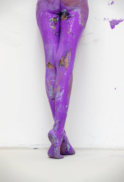 back view to beautiful legs and feet on tiptoe of a sexy young artistically abstract painted nude woman, ballerina with pink, purple paint from behind, creative bodypainting, copy space. - Photo, image