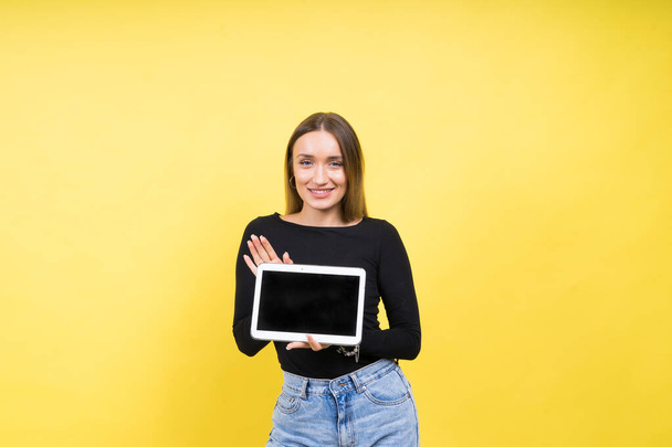 Smart intelligent caucasian young woman student using digital tablet isolated on yellow background - Photo, Image