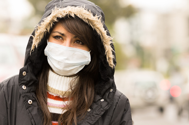 young girl walking wearing jacket and a mask in the city street concept of  pollution - Фото, изображение