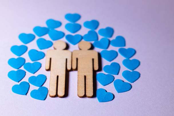 Male love LGBT. Same-sex family icons. gay couple of two homosexual men. The male couple is holding hands. Wooden people with paper blue hearts - Foto, Imagem