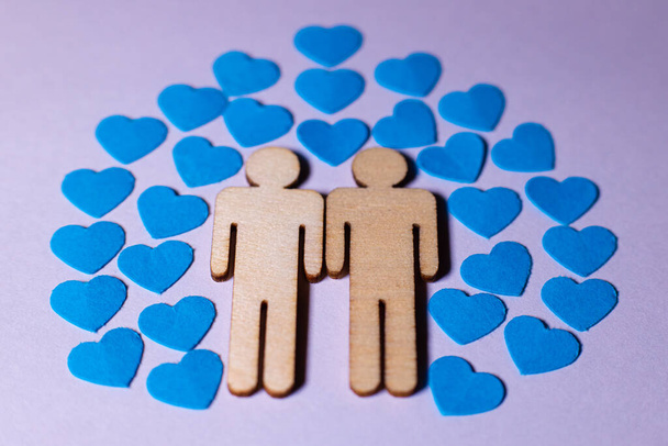 Male love LGBT. Same-sex family icons. gay couple of two homosexual men. The male couple is holding hands. Wooden people with paper blue hearts - Photo, Image