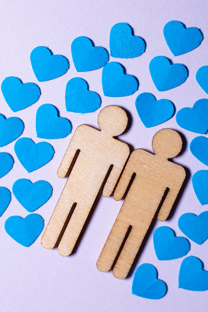 Male love LGBT. Same-sex family icons. gay couple of two homosexual men. The male couple is holding hands. Wooden people with paper blue hearts - Foto, imagen
