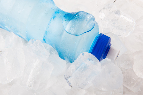 Uma garrafa de água mineral em cubos de gelo
 - Foto, Imagem