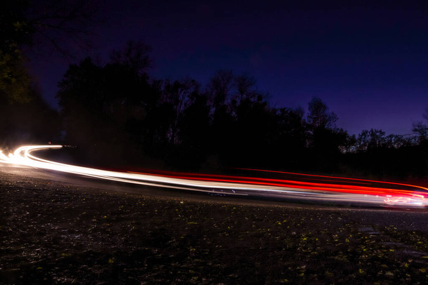 Nachtlicht-Malerei mit Autos, die in einer gebogenen Straße fahren - Foto, Bild