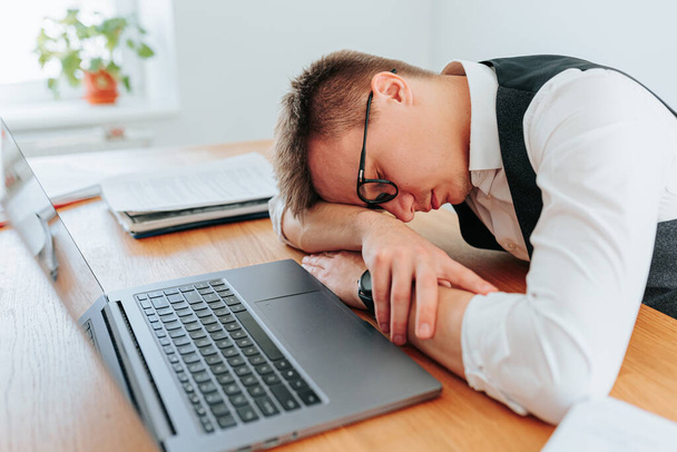 A man with glasses rests his head on his desk, seeking a brief period of slumber to refresh his mind and body before tackling the next project. Rest How Workers are Rediscovering the Benefits Napping - Фото, зображення