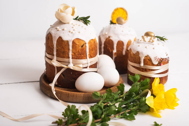 Easter cakes with a delicate, light, modern design nd eggs on a white wooden background with yellow daffodils. Easter concept. Easter traditional food. Easter symbol - Foto, immagini