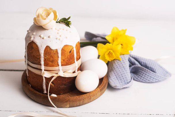Velikonoční koláče s jemným, lehkým, moderním designem a vajíčky na bílém dřevěném pozadí se žlutými narcisy. Velikonoční koncept. Velikonoční tradiční jídlo. Velikonoční symbol - Fotografie, Obrázek