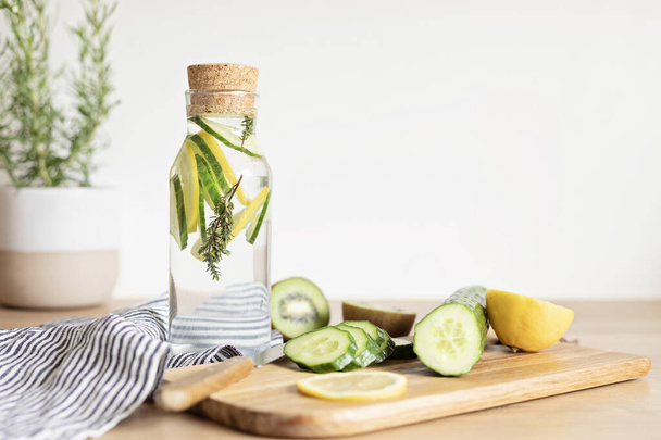 Infused  water with cucumber, lemon and thyme in glass bottle on wooden table. Diet, detox, healthy eating, weight loss concept - Foto, Imagem