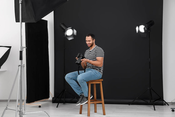 Young professional photographer with camera in modern photo studio - Fotoğraf, Görsel