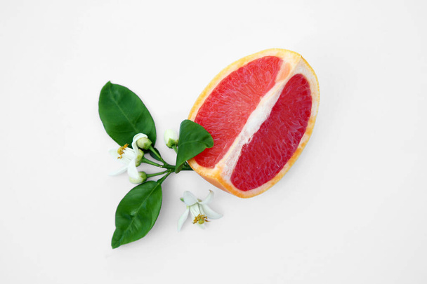 Cut fresh ripe grapefruit and green leaves on white background, top view - Valokuva, kuva