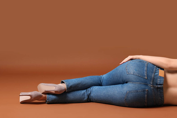Woman in stylish jeans on brown background, closeup. Space for text - Foto, immagini