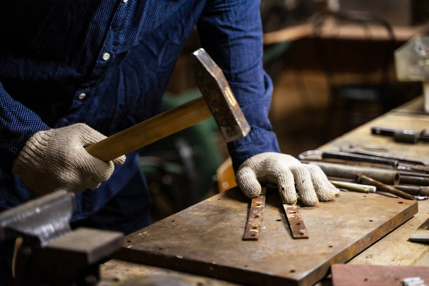 A man works with a hammer in a workshop. - Foto, Imagem