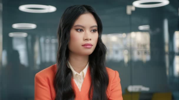 Concentrated professional girl with pretty face hair posing for close up portrait indoors. Confident thoughtful young Asian stylish business woman standing at office attentively listening colleague 4K - Footage, Video
