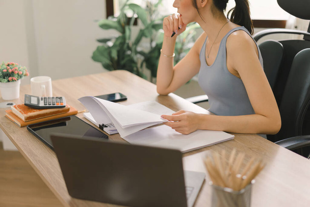 A cropped shot shows a millennial businesswoman of a startup working with financial report paperwork in her home office. The concept of financial advising teamwork and accounting is depicted - Fotoğraf, Görsel