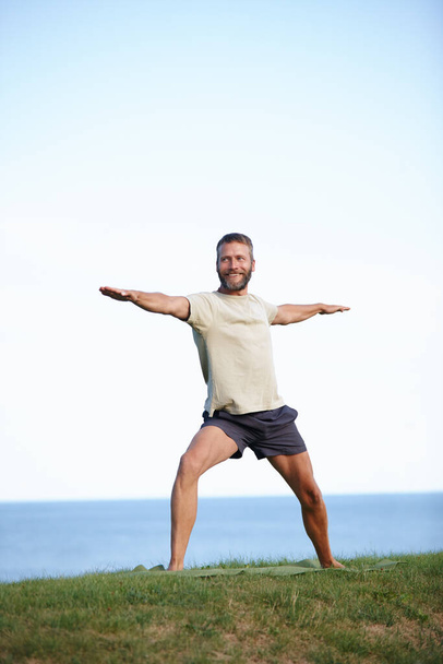 Guerrero al aire libre. De cuerpo entero de un guapo hombre maduro haciendo yoga al aire libre - Foto, Imagen