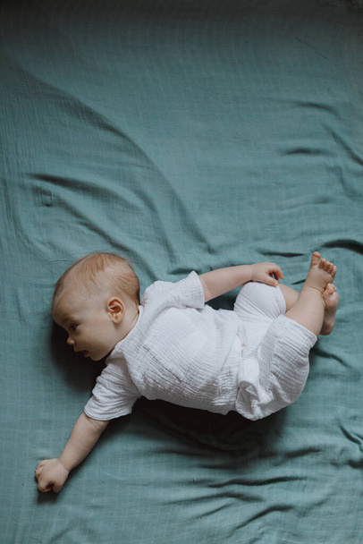Vista superior de gran angular bebé recién nacido se encuentra en una cuna brazos. Un bebé recién nacido descansa en la cama. Guardería infantil para niños pequeños. Textiles y ropa de cama para niños. Mañana familiar en casa. - Foto, Imagen