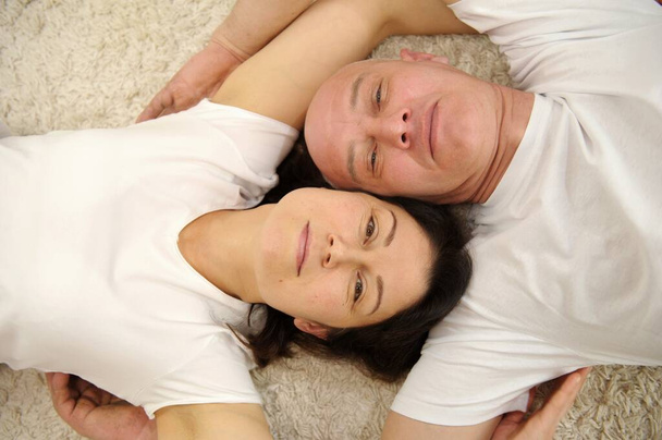 Ευτυχισμένος άντρας και γυναίκα ξαπλωμένοι στο κρεβάτι και χαμογελαστοί. Υψηλής ποιότητας φωτογραφία - Φωτογραφία, εικόνα