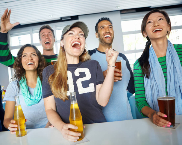 Score. A group of friends cheering on their favourite sports team at the bar - Photo, Image